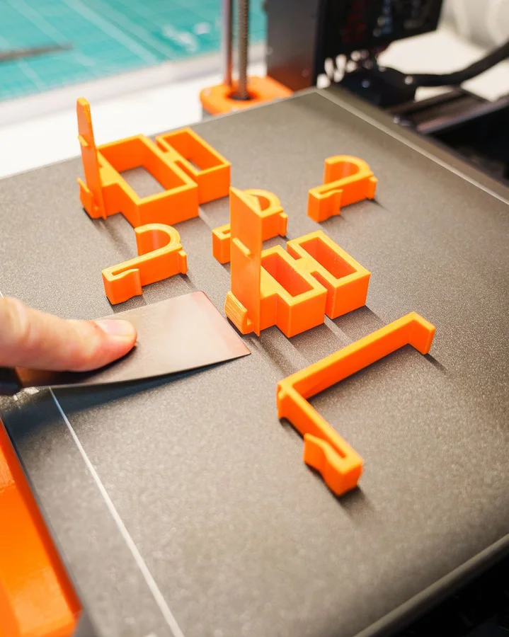 Freshly 3D printed replacement clips being lifted off the build plate